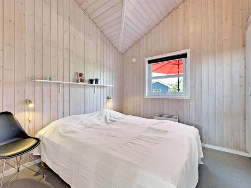 a bedroom with a bed and a chair and a window at Holiday Home Chrisse - 550m from the sea by Interhome in Lakolk