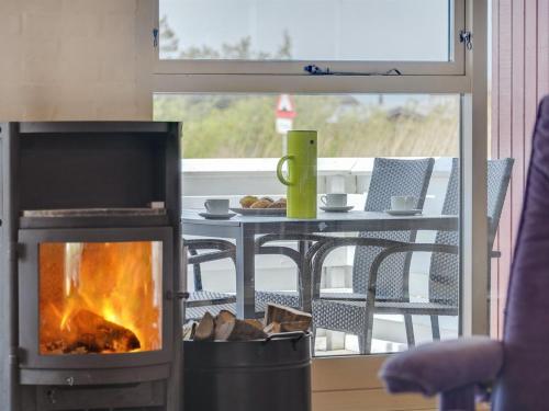 a fireplace in a living room with a table at Holiday Home Hermandine - 700m from the sea by Interhome in Lakolk