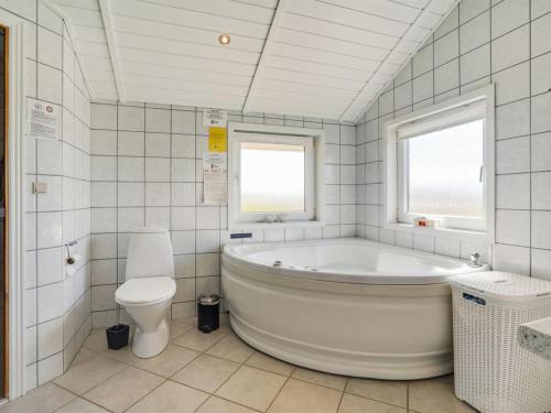 a white bathroom with a tub and a toilet at Holiday Home Freek - 400m from the sea by Interhome in Lakolk