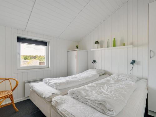 two beds in a room with a window at Holiday Home Freek - 400m from the sea by Interhome in Lakolk