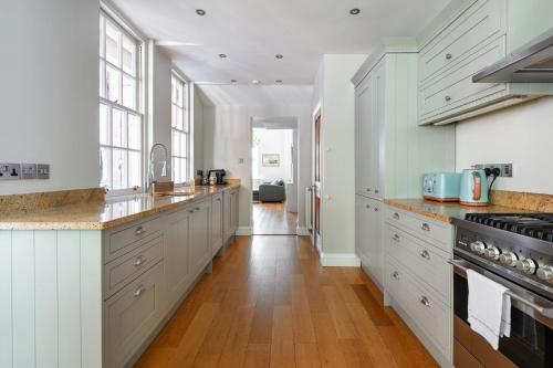 a kitchen with white cabinets and a wooden floor at Castle View in Windsor