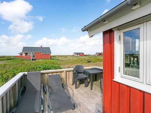 a deck with a table and chairs and a red house at Holiday Home Mortensen - 350m from the sea by Interhome in Lakolk