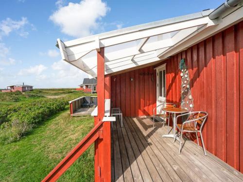 a deck with a table and chairs on a red building at Holiday Home Mortensen - 350m from the sea by Interhome in Lakolk