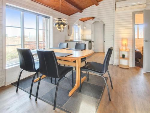 a dining room with a wooden table and black chairs at Holiday Home Hendrine - 500m from the sea by Interhome in Lakolk
