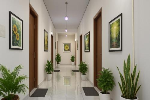 a hallway with potted plants and paintings on the walls at Ramayana Grand Hotel Ayodhya - A Step Away from Shri Ram Mandir in Ayodhya