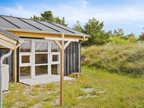 a small black and white shed with a large window at Holiday Home Alessia - 2km from the sea by Interhome in Lakolk