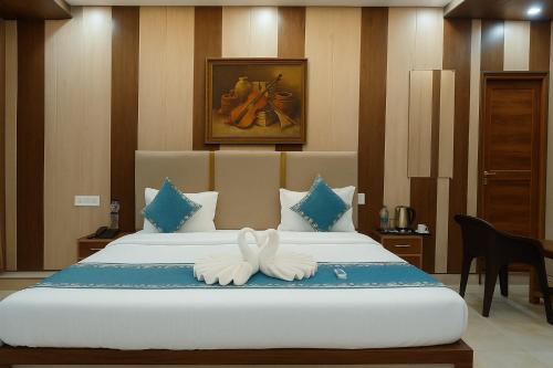 a bedroom with a large bed with two white towels at Ramayana Grand Hotel Ayodhya - A Step Away from Shri Ram Mandir in Ayodhya