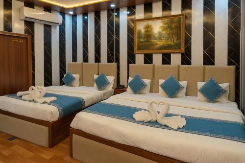 two beds in a room with swans on them at Ramayana Grand Hotel Ayodhya - A Step Away from Shri Ram Mandir in Ayodhya