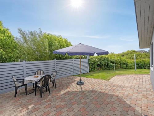 a table and chairs with an umbrella on a patio at Holiday Home Elise - 800m from the sea by Interhome in Lakolk