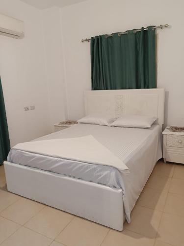 a white bed in a room with a green curtain at Dahab Hills Resort in Dahab