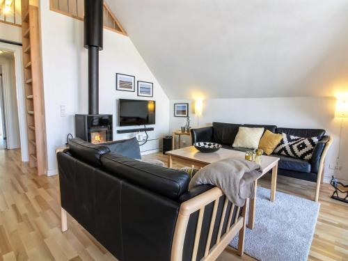 a living room with a black leather couch and a table at Holiday Home Eda - 3-5km from the sea by Interhome in Kongsmark
