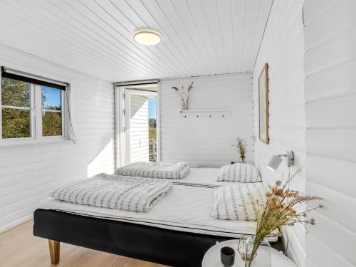 a bed in a white room with a window at Holiday Home Aika - 500m from the sea by Interhome in Lakolk