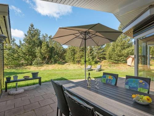 a wooden table with an umbrella on a patio at Holiday Home Bogatin - 1km from the sea by Interhome in Mølby