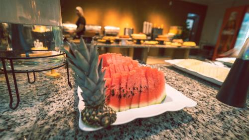 a slice of watermelon and a pineapple on a counter at Pousada Itajuípe- Unidade Itabuna-Ba in Itabuna