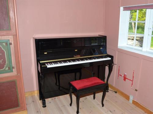 a black piano in a room with a red stool at Holiday Home Botmund - 3-6km from the sea by Interhome in Bolilmark