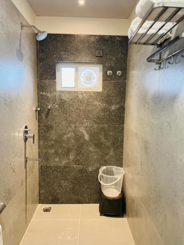 a bathroom with a shower with a window and a trash can at Hotel Skyview Suites & Studios in Hyderabad