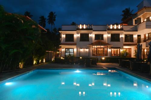 a swimming pool in front of a house at night at Vaarsa by Bay Hotels in Alibaug