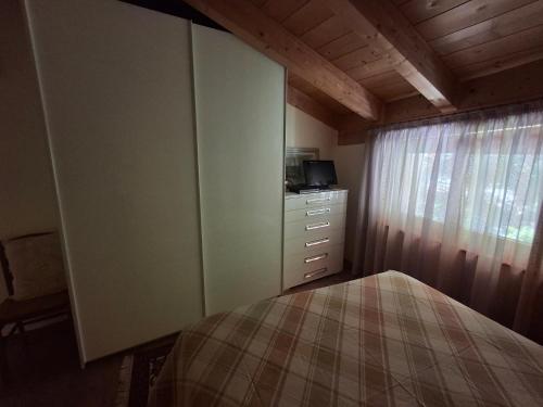 a bedroom with a bed and a dresser and a window at Chalet Cà Modest in Grosotto