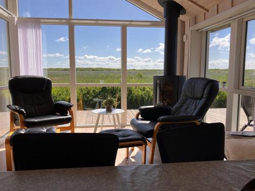 a living room with three chairs and a large window at Holiday Home Jonna - 700m from the sea by Interhome in Lakolk