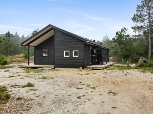 une cabine noire au milieu d'un champ dans l'établissement Holiday Home Turkka - 3-8km from the sea by Interhome, à Tagholm