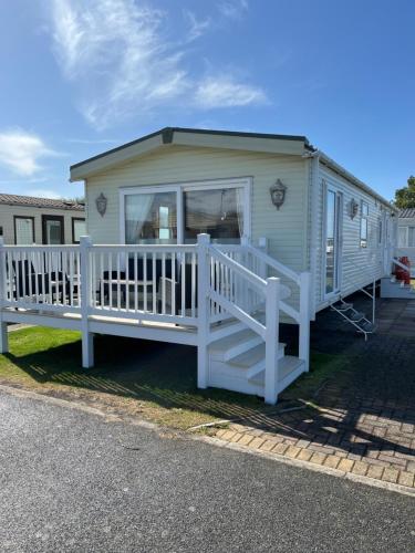 a mobile home with a porch and a white railing at 2 Bedroom Mini Lodge near the beach in Walton-on-the-Naze