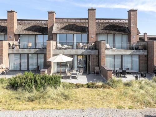 un edificio con mesas, sillas y sombrilla en Apartment Helgo - 250m from the sea by Interhome, en Sønderby