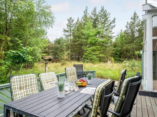 a wooden table on a deck with chairs at Holiday Home Aamu - 300m to the inlet by Interhome in Oksbøl