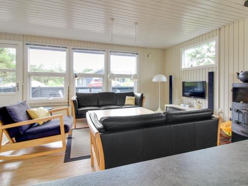ein Wohnzimmer mit einer schwarzen Couch und einem Fernseher in der Unterkunft Holiday Home Nanouk - 500m from the sea by Interhome in Vejers Strand