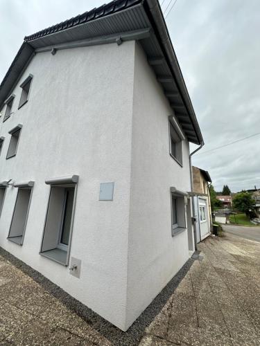 a white building with windows on the side of it at Große 2 Ferienwohnung Gästehaus NEUBAU Merzig 100 m2 in Merzig