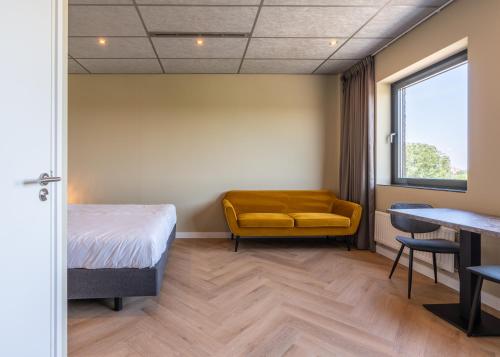 a room with a bed and a yellow chair at MyHotel Meppel in Meppel