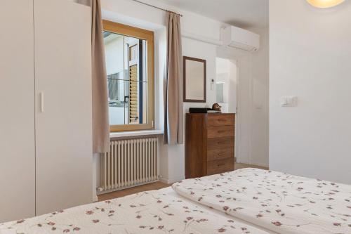 a white bedroom with a bed and a window at Auelehof Laives in Laives