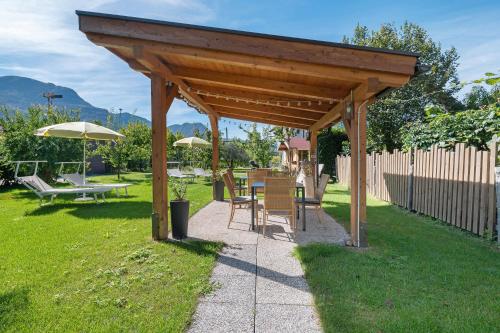 a wooden pavilion with chairs and tables in a yard at Auelehof Laives in Laives