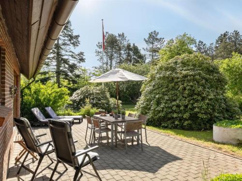 a patio with a table and chairs and an umbrella at Holiday Home Iiro - 2-5km from the sea by Interhome in Rømø Kirkeby
