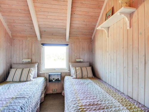 two beds in a small room with a window at Holiday Home Annalise - 1km from the sea by Interhome in Vejers Strand