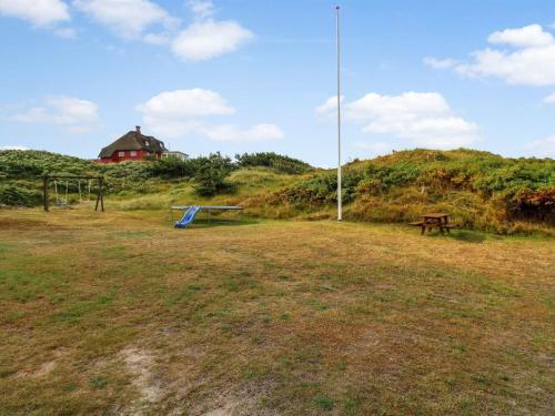 a field with a bench and a house on a hill at Holiday Home Dragan - 350m from the sea by Interhome in Vejers Strand