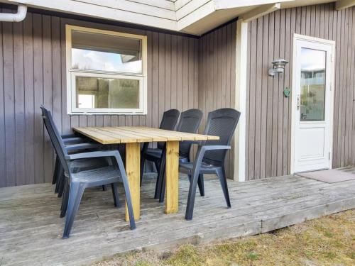 a wooden table and chairs on a deck at Holiday Home Dalia - 200m from the sea by Interhome in Vejers Strand