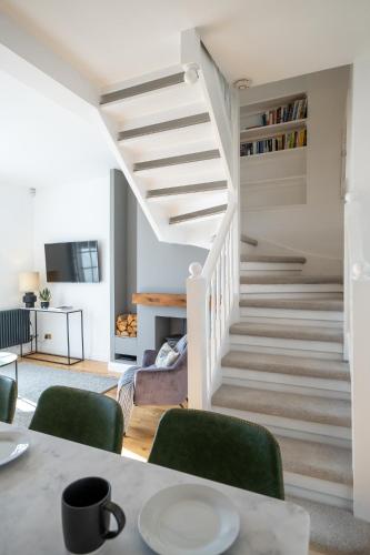 a living room with a staircase with green chairs at Beautiful Mews Cottage near Brighton Seafront in Rottingdean Village in Rottingdean
