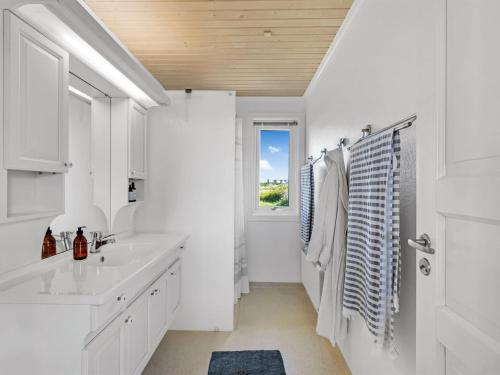 a white bathroom with a sink and a window at Holiday Home Aise - 75m from the sea by Interhome in Vejers Strand