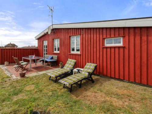 a red building with two chairs and a table and a patio at Holiday Home Aukusti - 600m from the sea by Interhome in Vejers Strand