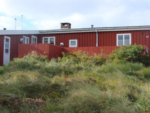 a red building with a fence in the grass at Holiday Home Aukusti - 600m from the sea by Interhome in Vejers Strand