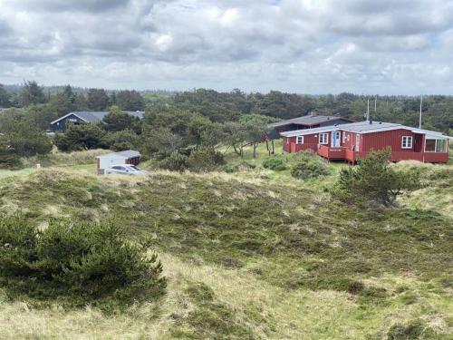 a red house on a grassy hill with houses at Holiday Home Aukusti - 600m from the sea by Interhome in Vejers Strand