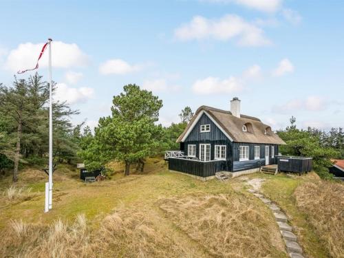 una casa negra en una colina con una bandera en Holiday Home Erikke - 300m from the sea by Interhome, en Vejers Strand