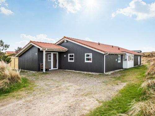 a black house with a red roof at Holiday Home Petkana - 700m from the sea by Interhome in Vejers Strand