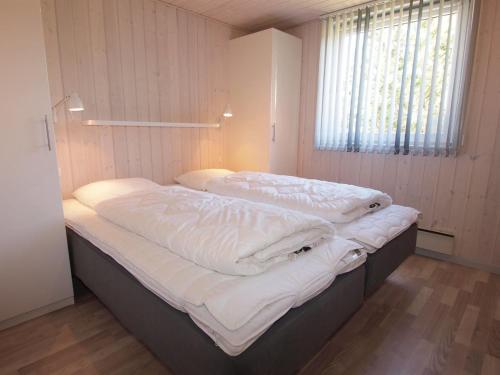 two twin beds in a room with a window at Holiday Home Emmarenze - 400m from the sea by Interhome in Blåvand