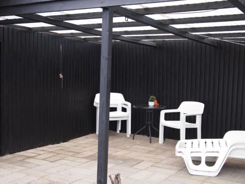 un patio couvert avec des chaises blanches et une table dans l'établissement Holiday Home Dane - 500m from the sea by Interhome, à Blåvand