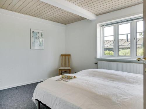 a white bedroom with a bed and a window at Holiday Home Stefan - 500m from the sea by Interhome in Blåvand