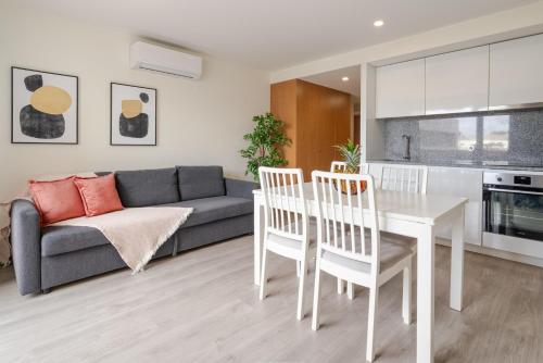 a living room with a couch and a table and chairs at Modern & Sleek Flat | Terrace & Garage by HostWise in Porto