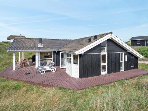 a black and white house with a deck at Holiday Home Asvalde - 150m from the sea by Interhome in Vejers Strand
