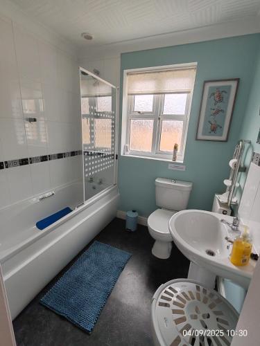 a bathroom with a toilet and a tub and a sink at Deja Blue in Sutton on Sea