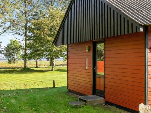 a red building with a door and a field at Holiday Home Aswaldi - 3-5km from the sea by Interhome in Blåvand